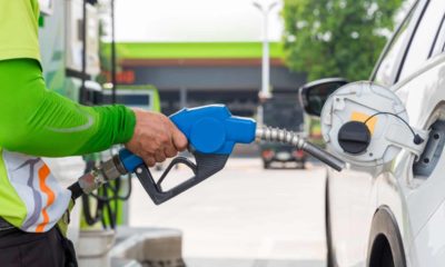 Hand holding gas nozzle with one last drop. A man holding a gasoline nozzle.