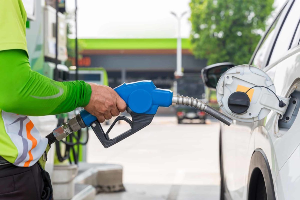 Hand holding gas nozzle with one last drop. A man holding a gasoline nozzle.